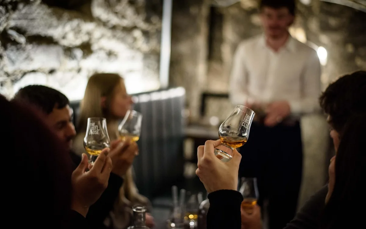 A glass of whisky held in both hands at a guided tasting